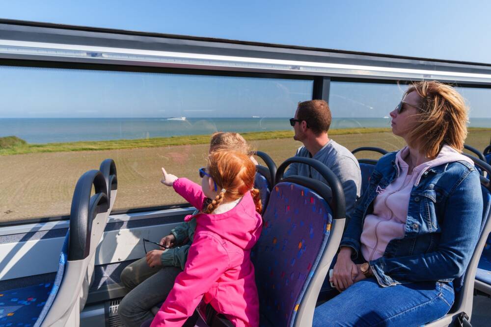 Une famille contemple la mer à l'horizon lors d'une escapade à bord de la Div'in, bus à impériale.