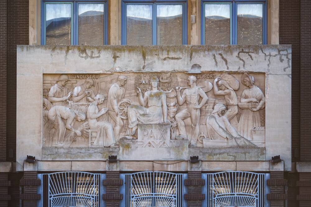 Detailed view of the crops on the façade of the Calais Labour Exchange, with the inscriptions 'Peace & Labour'