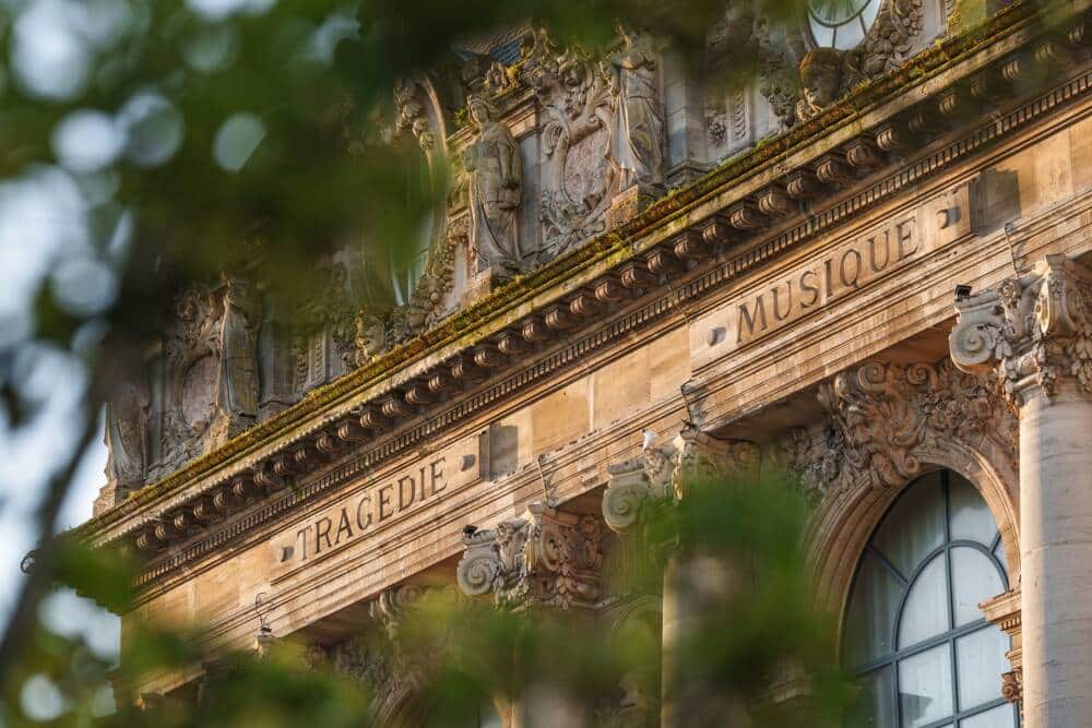 Détail architectural du Grand Théâtre de Calais, capturant la beauté de sa façade ornée des mots “Tragédie” et “Musique”. Un patrimoine emblématique qui témoigne de l’histoire culturelle de la ville, sublimé par la lumière dorée du soir.