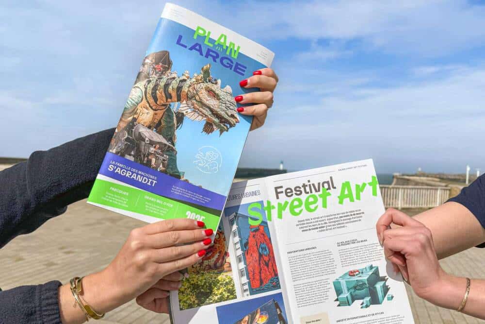 Photo de deus personnes présentant le Magazine Plan Large sur le front de mer de Calais