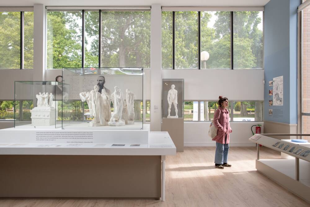Vue intérieure de la Galerie Rodin du musée des Beaux-Arts de Calais, avec une visiteuse contemplant des maquettes préparatoires du groupe des Bourgeois de Calais.