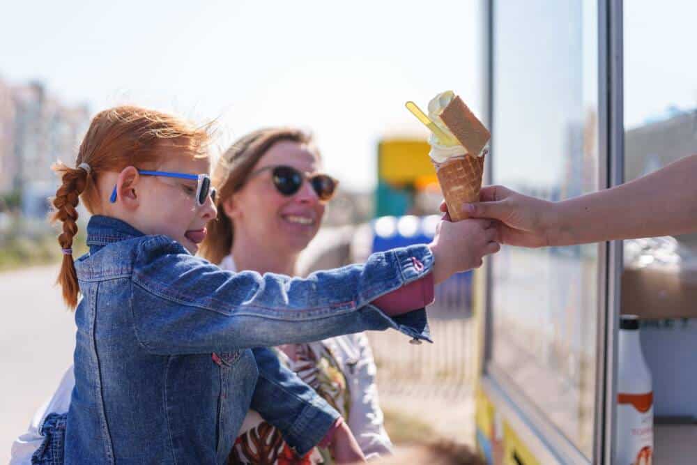 Une jeune fille récupère sa glace sur la plage de Calais auprès de l'un des deux camions emblématiques de Diego ou Sigler.