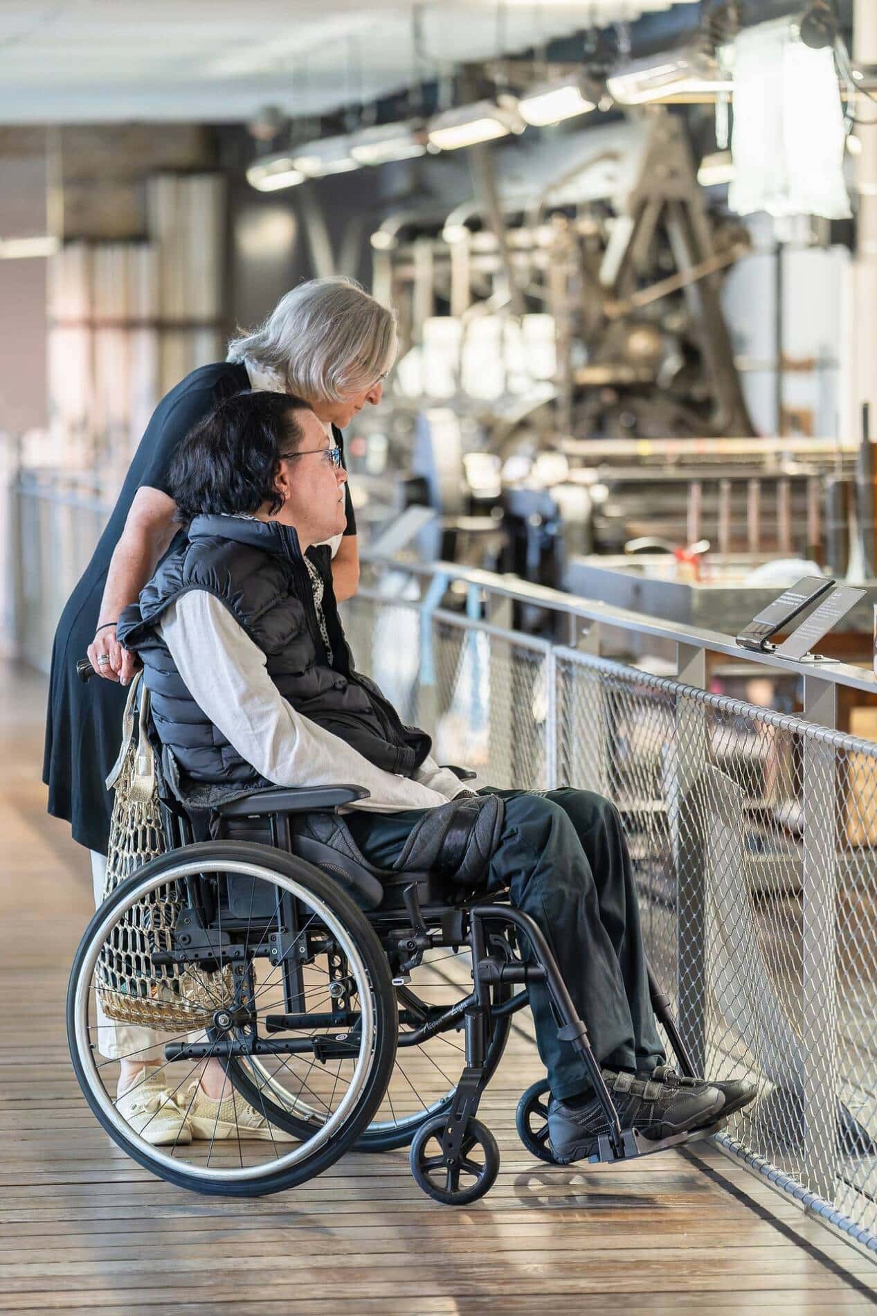 Une personne à mobilité réduite, en fauteuil, accompagnée pour la démonstration des Métiers Leavers.
