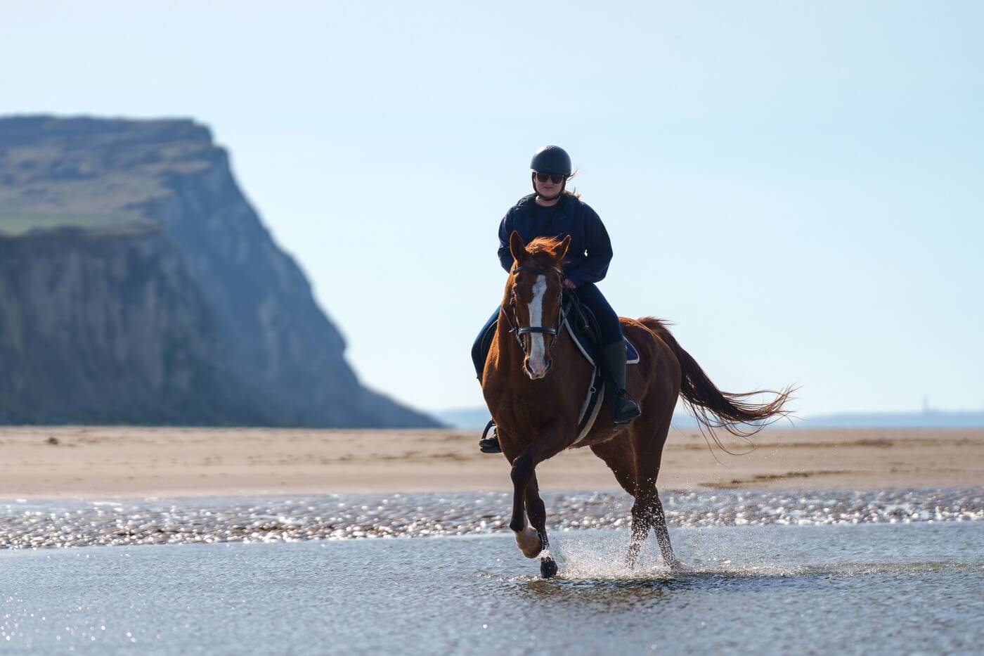 Constance et son cheval Gatsby s'ébrouant dans l'eau à marée basse sur les plages du Cap Blanc nez.