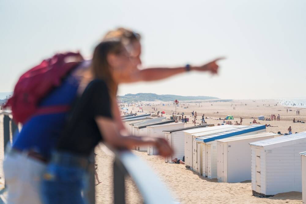 Couple scrutant l'horizon sur le belvédère de la plage de Calais, avec les chalets emblématiques en contrebas.
