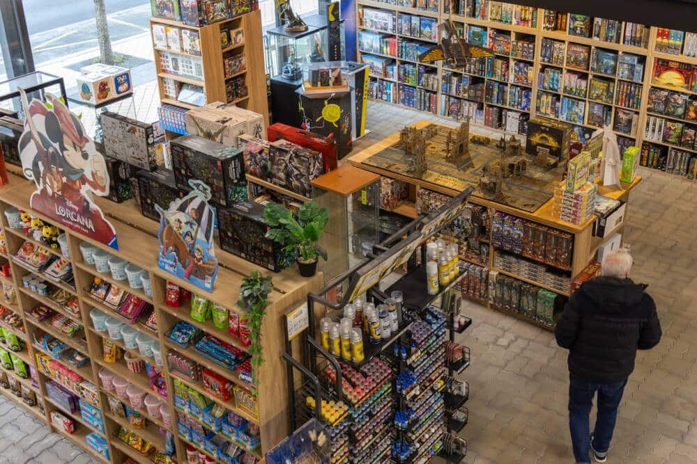Intérieur de la boutique La Caverne du Jeu avec rayonnages de jeux de société et figurines vus en plongée.